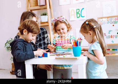 Professeur d'anglais avec enfants, amusez-vous et jouez à des jeux, apprenez l'alphabet et les numéros par les arts dans le centre de garde d'enfants Banque D'Images