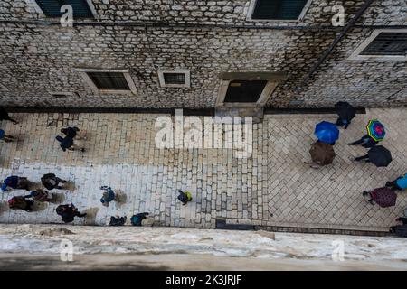 Vue aérienne des touristes avec des parasols marchant dans la pluie sur le pavé humide d'une allée dans la vieille ville de Dubrovnik, Croatie. Banque D'Images