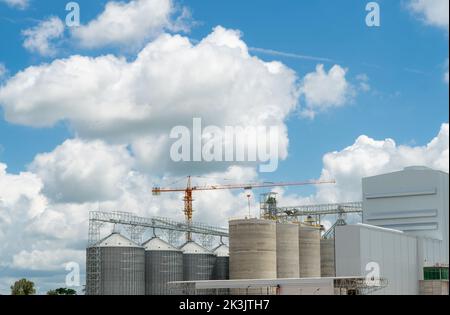 Site de construction de l'usine d'alimentation animale. Silo agricole à l'usine d'alimentation. Trémie pour le stockage du grain et grue de construction. Tour de stock de semences Banque D'Images