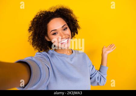 Portrait de gaie charmante fille faire selfie enregistrer vidéo bras paume démontrer l'espace vide isolé sur fond jaune couleur Banque D'Images