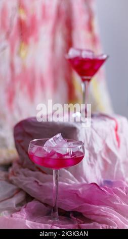 Photo verticale d'une tasse remplie de cocktails placée devant un fond rose Banque D'Images