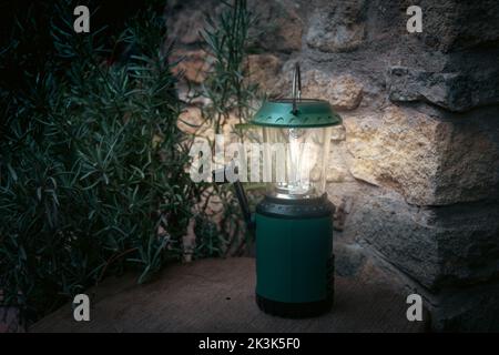 lumière amping ou lanterne, solaire et vent, gadget extérieur pour glamping dehors à côté du mur de pierre. Banque D'Images