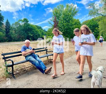 Bien qu'ils soient à Prospect Park par une belle journée d'été, tout le monde semble être collé à leurs téléphones portables à Brooklyn, New York. Banque D'Images