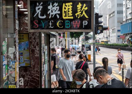 Les piétons marchent devant un bureau de change avec un panneau offrant: US Dollar ($), Japanese yen (¥), British Pound (£), Euro (€), Bitcoin (BTC, BCH), Korean Won et Cuba Peso. Banque D'Images