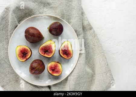 Figues mûres fraîches sur une assiette sur une table blanche. Vue de dessus, plan d'appartement. Banque D'Images