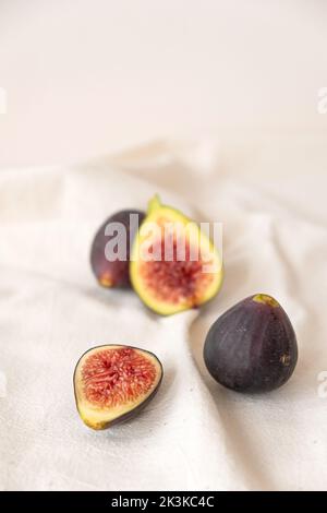 Figues fraîches mûres et douces coupées et entières sur toile de table beige. Banque D'Images