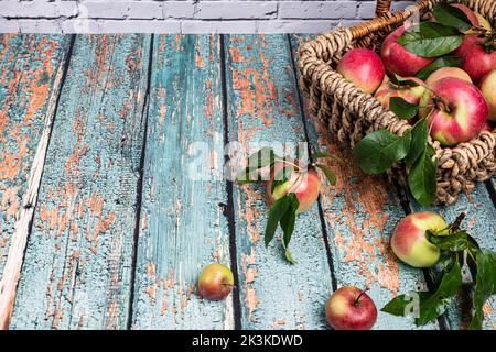 panier tressé décoratif avec pommes rouges fraîches sur un vieux plan d'examen Banque D'Images