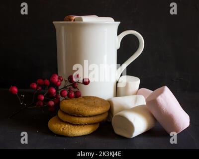 Chocolat chaud avec guimauves et biscuits au gingembre sur fond noir Banque D'Images