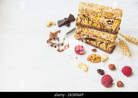 Une pile de barres de granola maison avec des noix, des graines, du chocolat noir, du miel et des baies sur un fond blanc. Copier l'espace. Banque D'Images