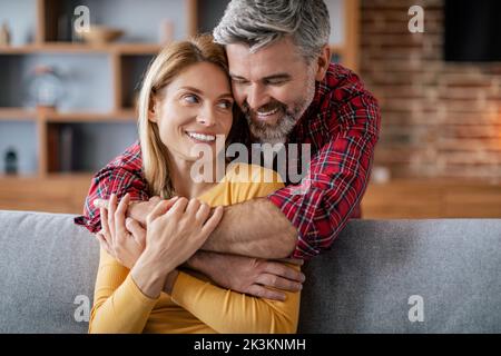 Joyeux homme d'âge européen, profitez du confort et de la romance sur le canapé dans le salon confortable Banque D'Images