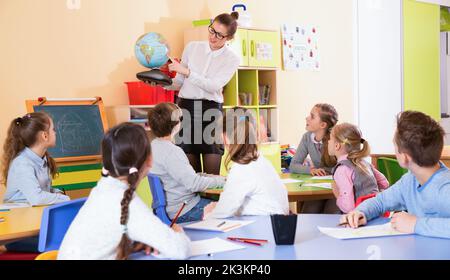 Enseignante donnant une leçon de géographie en classe, montrant les élèves du monde entier Banque D'Images