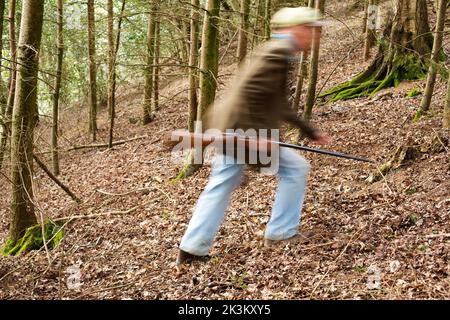 Une image de blury d'un homme qui marche à travers les bois a un fusil Banque D'Images