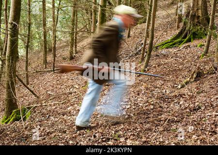 Une image de blury d'un homme qui marche à travers les bois a un fusil Banque D'Images