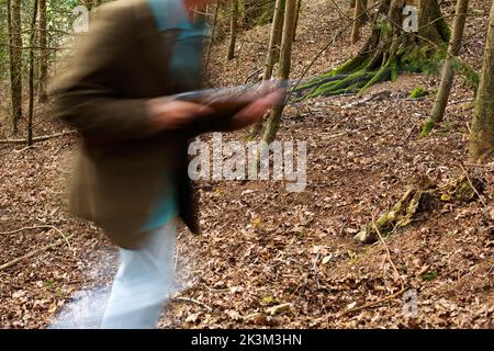 Une image de blury d'un homme qui marche à travers les bois a un fusil Banque D'Images