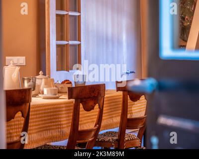 Une table à l'ancienne avec de vieilles chaises en bois et une nappe à carreaux blancs et jaunes Banque D'Images