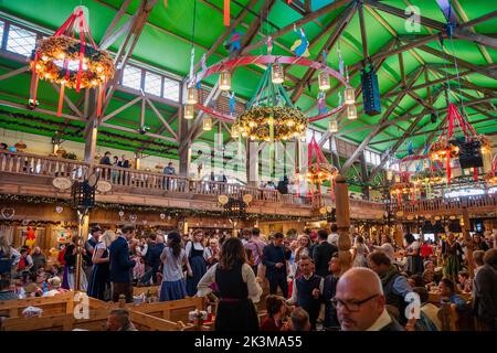 Personnes assises dans une tente à bière à l'Oktoberfest de Munich. Célébrez des gens joyeux qui boivent de la bière au festival folklorique de renommée mondiale, dansant à la musique bavaroise Banque D'Images