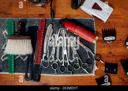 Vue de dessus de divers instruments de coiffure, y compris ciseaux coupe-herbes peignes rasoir et brosse placés sur une serviette sur une table en bois dans le salon de coiffure Banque D'Images