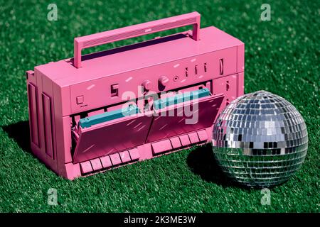 Boule disco argentée brillante placée près du lecteur de cassettes vintage et des cassettes sur l'herbe dans le studio Banque D'Images