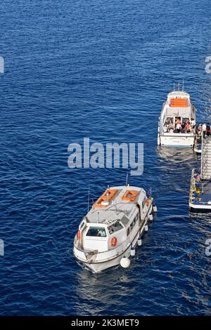 Mykonos, Grèce - Mai 2022 : petits bateaux à moteur collectant les passagers d'un bateau de croisière amarré au large de l'île grecque de Mykonos Banque D'Images