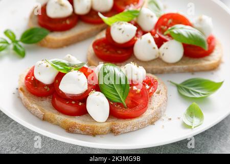 Toasts de Caprese avec mini-fromage mozzarella, tomates cerises et basilic Banque D'Images