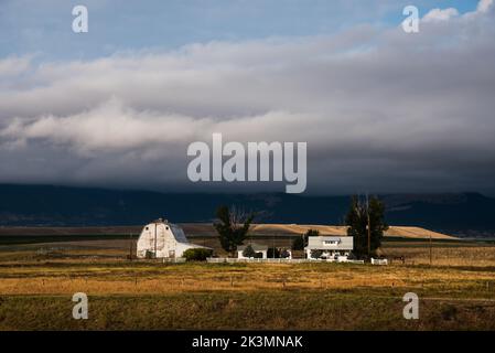 Grange blanche et ferme à Deer Lodge, Montana, États-Unis. Le Montana est connu sous le nom de « grand pays du ciel » pour ses vastes espaces ouverts et sa population clairsemée. Banque D'Images