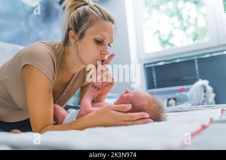 Bébé garçon de quelques mois criant et pleurant pendant un changement de couche. Sa mère montrant un signe shhh et essayant de calmer son fils. Photo de haute qualité Banque D'Images