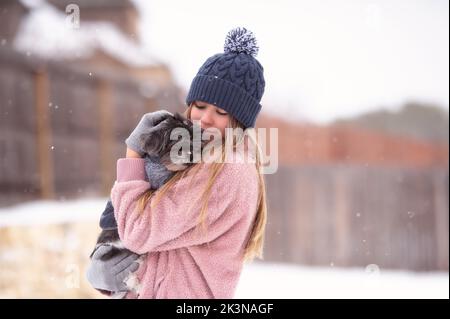 Un chien de Petting de fille dans la neige Banque D'Images