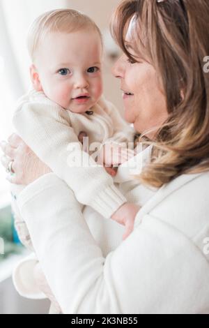 grand-mère de 60-69 ans sourit tenant un garçon de 1 an à noël. Banque D'Images