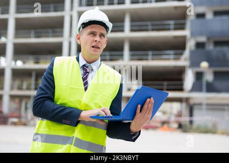 Homme souriant architecte dans un casque travaillant à l'extérieur de l'ordinateur portable Banque D'Images