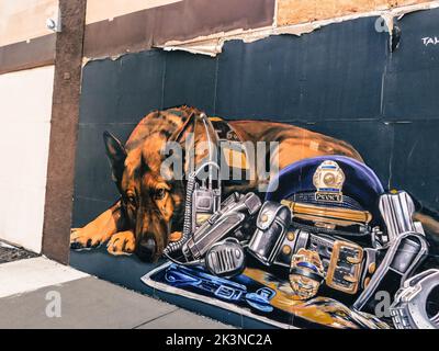 Une fresque d'un triste service police german berger couché par les objets de son partenaire mort Banque D'Images
