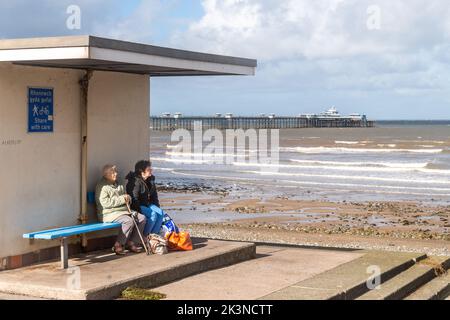 Personnes assises dans un abri sur la promenade de Llandudno, au nord du pays de Galles, au Royaume-Uni. Banque D'Images