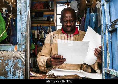 Nakuru, Kenya, 27/09/2022, Josephat Mureithi, frère de William Munuhe, journaliste kenyan tué, périt des lettres et des documents de la cour lors de son atelier d'électronique à Nakuru Town. Dirigé par Josephat, la famille de feu William Munuhe qui a été tué sur 14 janvier 2003, comme il a aidé la police et le Bureau fédéral des enquêtes (FBI) des États-Unis à traquer le fugitif de génocide rwandais, Felicien Kabuga, est toujours en quête de justice 19 ans plus tard. Felicien Kabuga (89), a été chassé de sa cachette en France après 26 ans en course et sera présenté au mécanisme résiduel international d'UNís pour l'IRC Banque D'Images