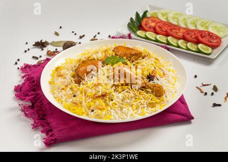 Dhum biriyani à base de riz et d'épices jeera disposés dans des ustensiles en terrine avec salade sur fond blanc. Banque D'Images