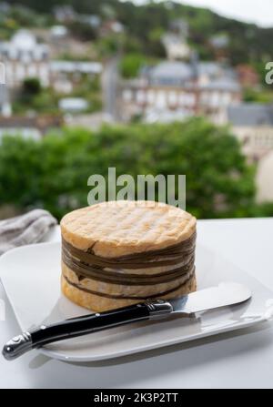 Dégustation de fromage de vache livarot jaune de Lisieux, région du Calvados et vue sur les maisons anciennes d'Etretat, Normandie, France Banque D'Images