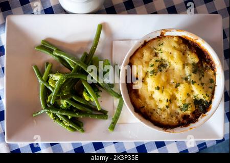 Tarte aux lentilles et aux champignons assaisonnée cuite lentement dans du vin rouge, recouverte de purée de cheddar et servie avec des légumes de saison de gros plan Banque D'Images