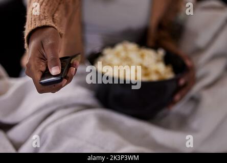 Heure TV. Photo en grand angle d'une femme méconnaissable mangeant du pop-corn tout en regardant la télévision à la maison. Banque D'Images