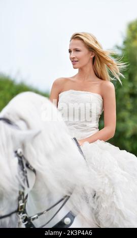 Elle est entrée dans son mariage à cheval. Une magnifique jeune mariée à cheval blanc le jour de son mariage. Banque D'Images