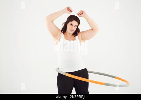 Se mettre en forme à sa manière. Vue rognée d'une femme dansant de hula tout en étant isolée sur blanc. Banque D'Images