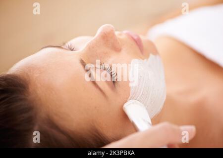 Application d'un masque de beauté. Gros plan d'un esthéticienne appliquant un masque facial à un client. Banque D'Images