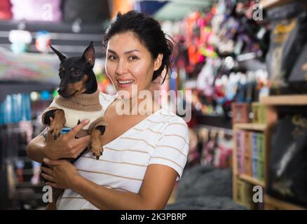 Femme orientale avec son petit chien dans la boutique d'animaux Banque D'Images