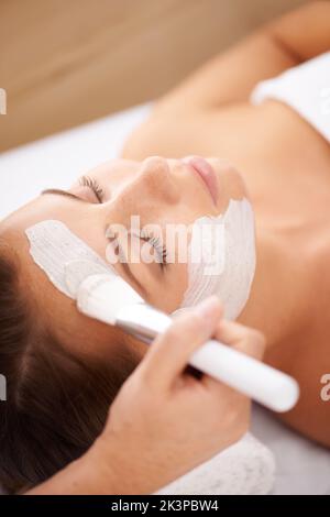 Application d'un masque de beauté. Gros plan d'un esthéticienne appliquant un masque facial à un client. Banque D'Images