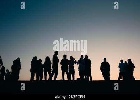 Nan, Thaïlande - 15 décembre 2021: Silhoueté personnes debout sur le bord de la crête de montagne attendant de voir le lever du soleil avec ciel bleu clair. Banque D'Images