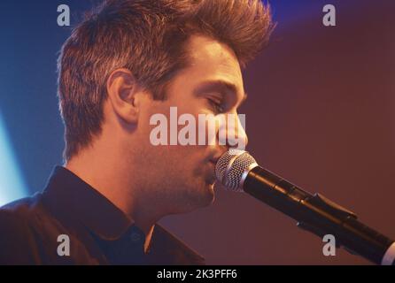 Un jeune interprète chantant dans un microphone. Ce concert a été créé dans le seul but de cette séance photo, avec 300 modèles et 3 groupes live Banque D'Images