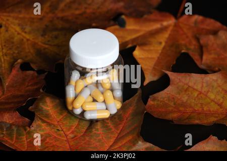 Pilules sur les feuilles d'érable d'automne, bouteille avec capsules. Pharmacie, antidépresseurs, vitamines pour l'immunité en saison de la grippe Banque D'Images