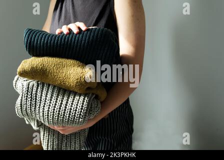 femme tenant dans sa pile de chandails chauds en laine et de cardigans Banque D'Images