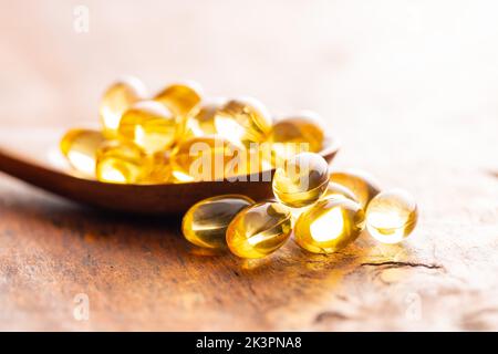 Capsules d'huile de poisson. Pilules jaunes oméga 3 en cuillère sur la table en bois. Banque D'Images