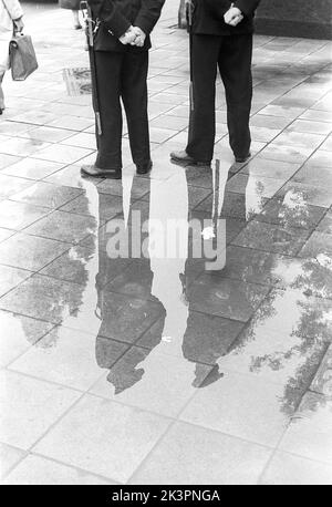 C'est un jour pluvieux à Stockholm Suède 1954. Les deux policiers sont visibles en pleine figure dans leur reflet dans la flaque de l'eau de pluie. Réf. 2A-1 Banque D'Images