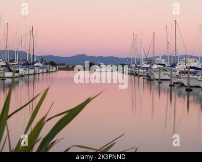 Des bateaux amarrés dans la marina au coucher du soleil de magnifiques roses et bleus reflétés dans l'eau calme. Banque D'Images