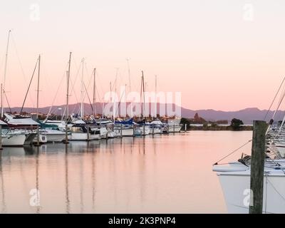 Des bateaux et des yachts amarrés dans la marina au coucher du soleil sous un ciel clair aux tons pastel. Banque D'Images