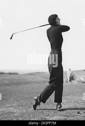 Golf dans le 1930s. Une jeune femme photographiée dans le moment après avoir frappé la balle de golf et cherche à voir si elle est sur le fairway ou pas. Angleterre 1930s Banque D'Images